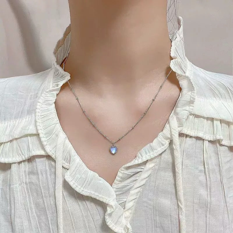Necklace with a heart-shaped pendant on a mannequin wearing a white blouse.